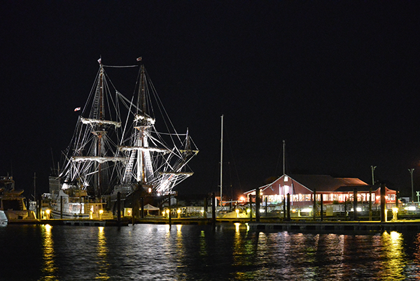 Night time image and reflection of a Tall Ship and Shanty at the Town Harbor